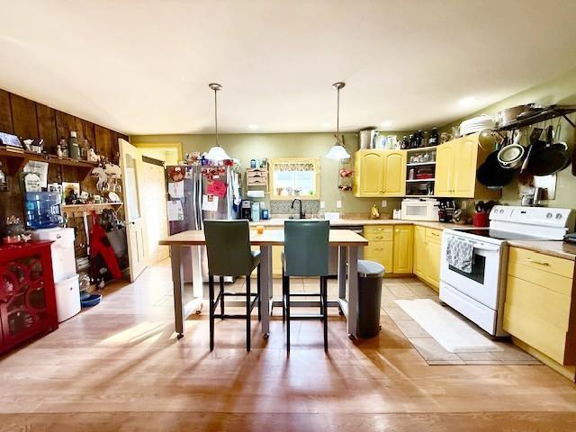 kitchen featuring open shelves, white appliances, light countertops, pendant lighting, and a sink