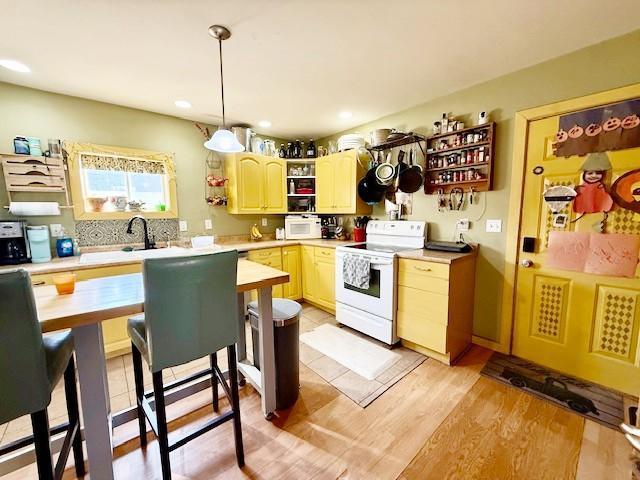 kitchen featuring a sink, hanging light fixtures, light countertops, white range with electric stovetop, and open shelves