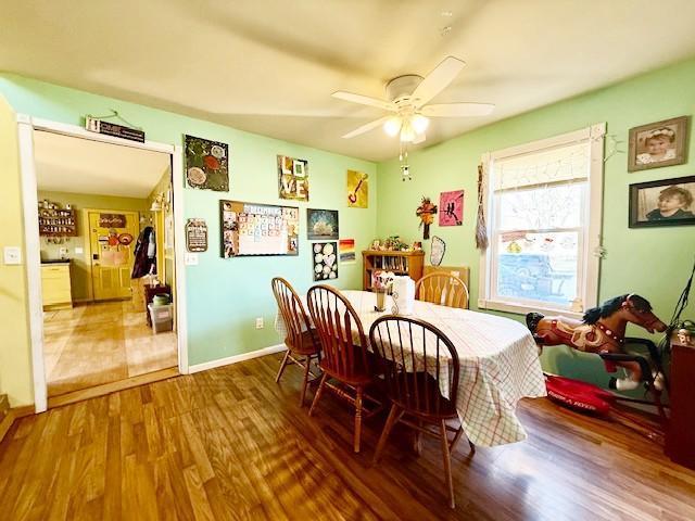 dining space featuring wood finished floors, a ceiling fan, and baseboards