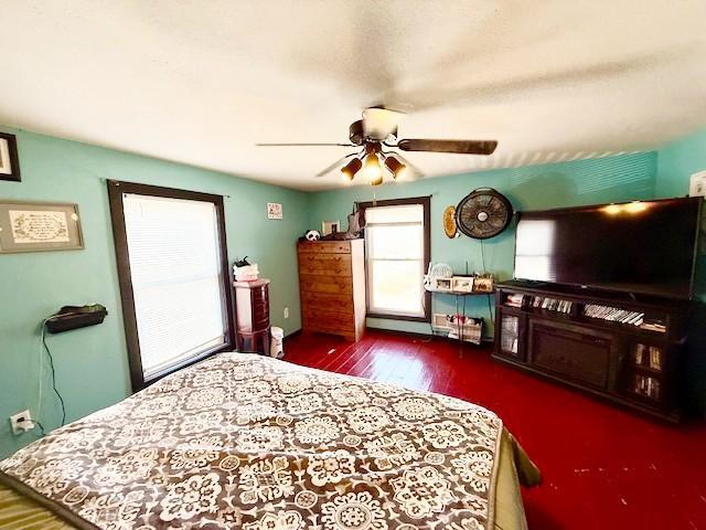 bedroom with a baseboard radiator, wood finished floors, and a ceiling fan