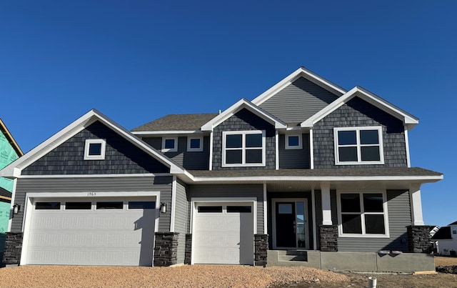 craftsman-style home with driveway, a porch, and stone siding