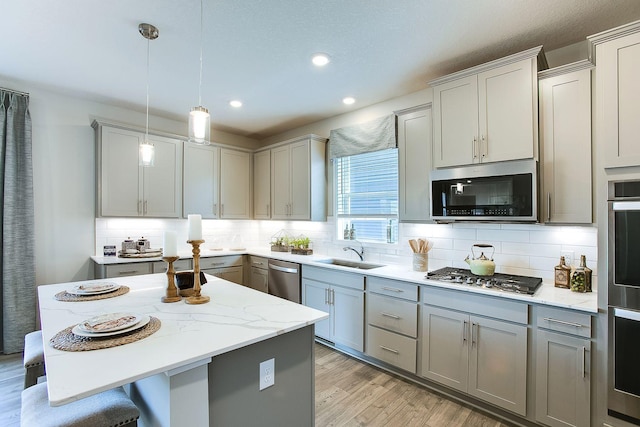 kitchen with light wood-style flooring, a sink, appliances with stainless steel finishes, gray cabinets, and tasteful backsplash