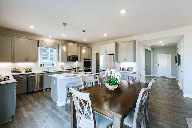 kitchen with appliances with stainless steel finishes, light countertops, a sink, and backsplash