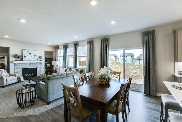 dining space with a textured ceiling, a fireplace, and wood finished floors