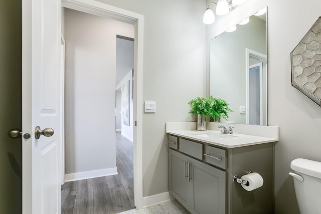 bathroom with wood finished floors, vanity, toilet, and baseboards