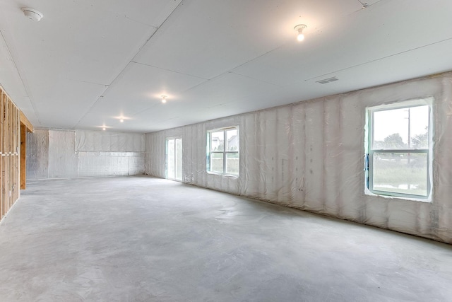 unfurnished room with plenty of natural light, visible vents, and unfinished concrete floors