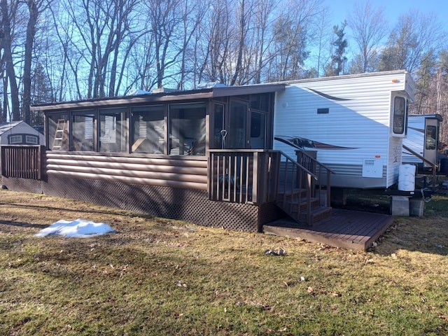 back of house featuring a sunroom, a lawn, and a storage shed