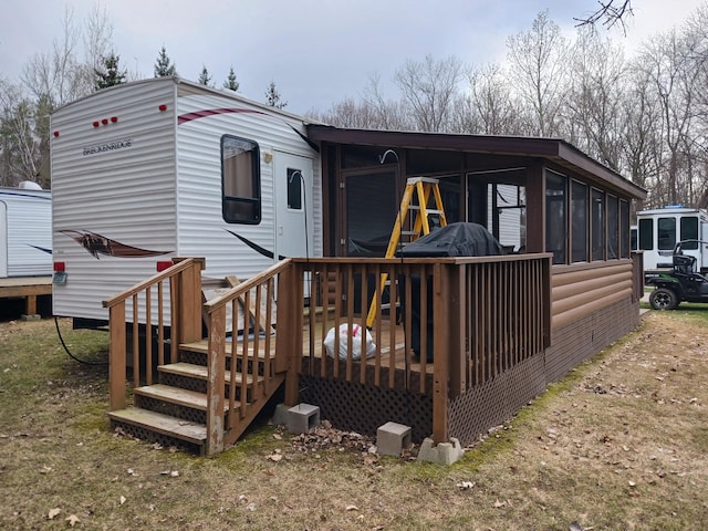 rear view of property featuring a sunroom and a wooden deck