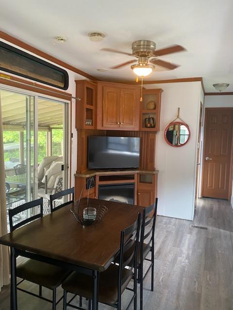 dining space with light wood finished floors, ceiling fan, and crown molding