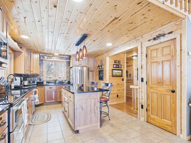 kitchen with light tile patterned floors, wooden ceiling, stainless steel appliances, dark countertops, and a kitchen bar