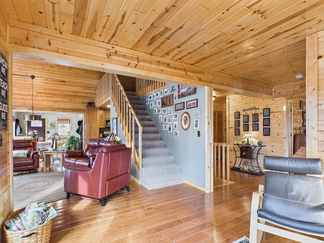 living room with light wood finished floors, wood ceiling, stairway, and wood walls