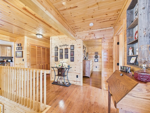 hallway featuring light wood-type flooring, wood ceiling, wood walls, and beam ceiling