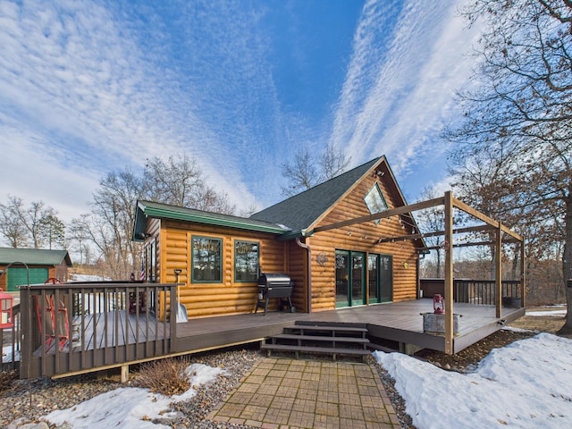 snow covered rear of property with a deck and log veneer siding