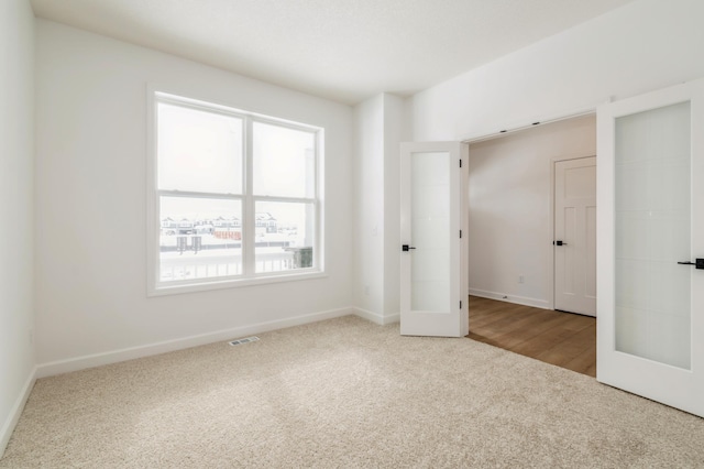 empty room featuring carpet floors, french doors, and visible vents