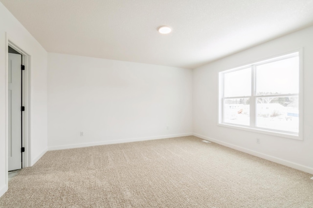 spare room with light carpet and baseboards