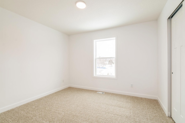 empty room with baseboards, visible vents, and light colored carpet