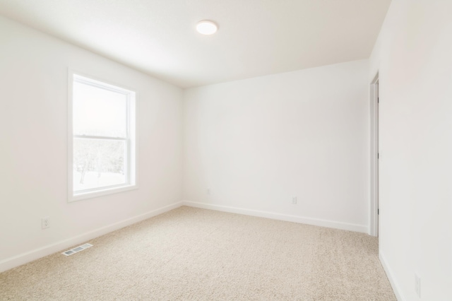 empty room featuring visible vents, light carpet, and baseboards