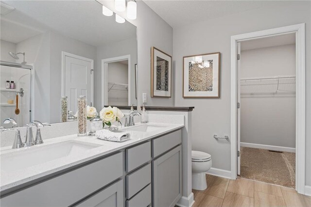 bathroom with double vanity, a sink, toilet, and an enclosed shower