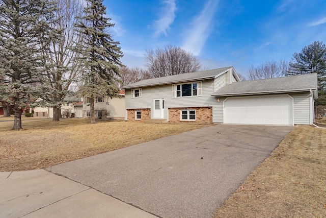 split foyer home with driveway, brick siding, and an attached garage