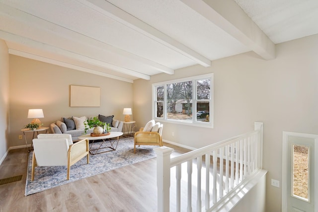 living area with beamed ceiling, baseboards, and wood finished floors