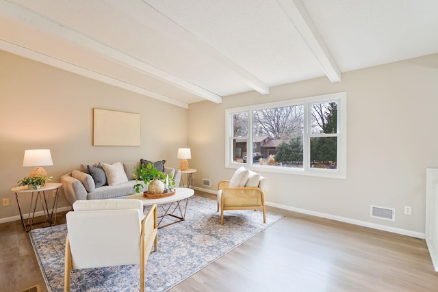 living area with vaulted ceiling with beams, baseboards, visible vents, and wood finished floors