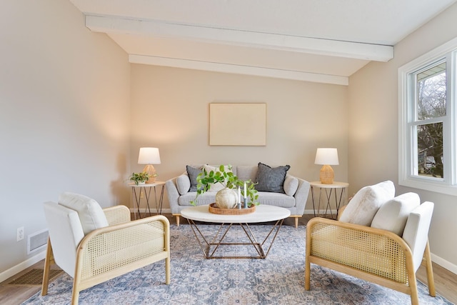 living area featuring vaulted ceiling with beams, visible vents, baseboards, and wood finished floors