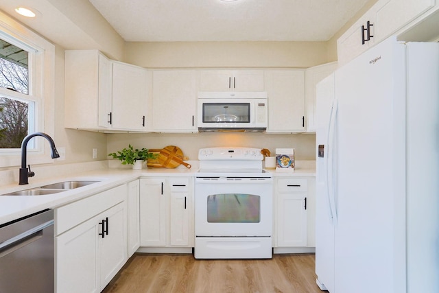 kitchen featuring white appliances, light wood-style flooring, light countertops, white cabinetry, and a sink