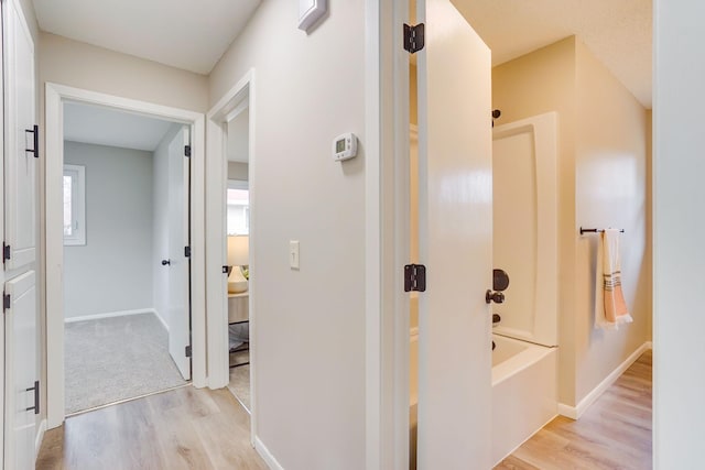 hallway with light wood-style flooring and baseboards