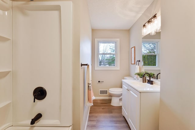 bathroom featuring baseboards, visible vents, toilet, wood finished floors, and vanity