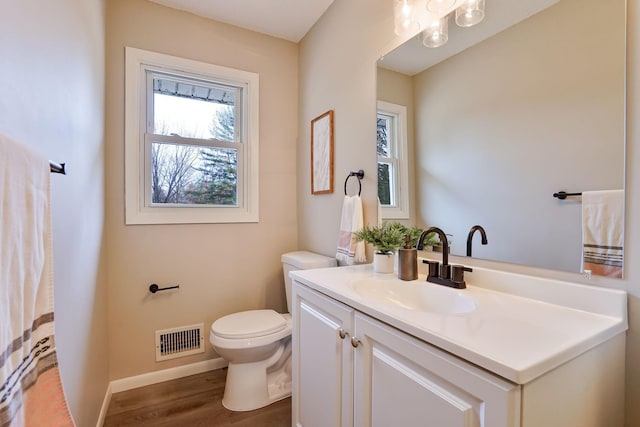 bathroom featuring toilet, wood finished floors, vanity, visible vents, and baseboards