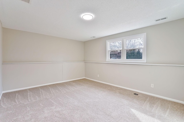 carpeted spare room featuring visible vents, a textured ceiling, and baseboards