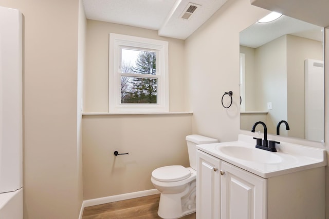 bathroom featuring visible vents, toilet, vanity, wood finished floors, and baseboards