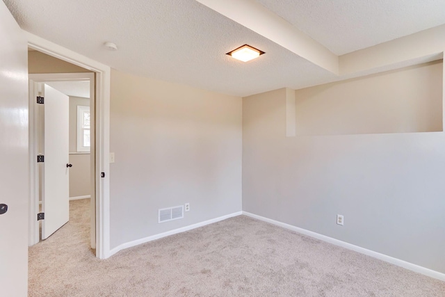 carpeted spare room featuring a textured ceiling, visible vents, and baseboards