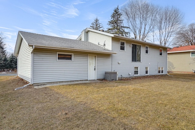 rear view of property featuring a yard, a shingled roof, and central AC