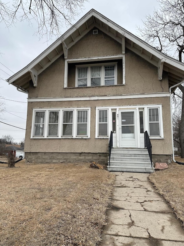 bungalow-style home with stucco siding