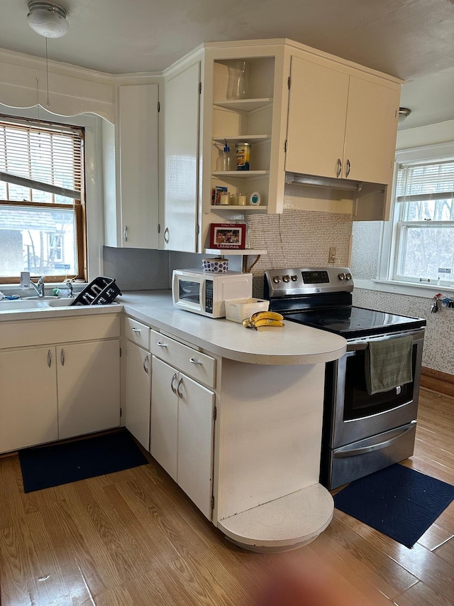 kitchen with white microwave, light countertops, electric stove, and wood finished floors