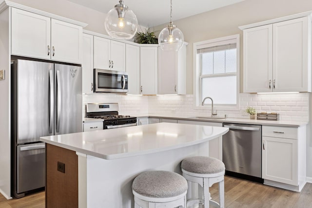 kitchen with light wood finished floors, backsplash, stainless steel appliances, and a sink