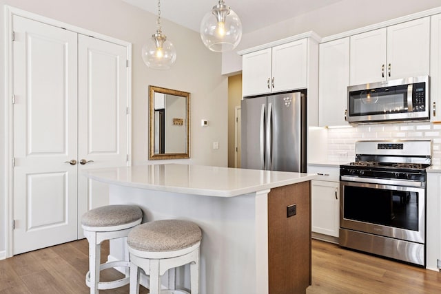 kitchen with light wood-type flooring, tasteful backsplash, stainless steel appliances, and a center island