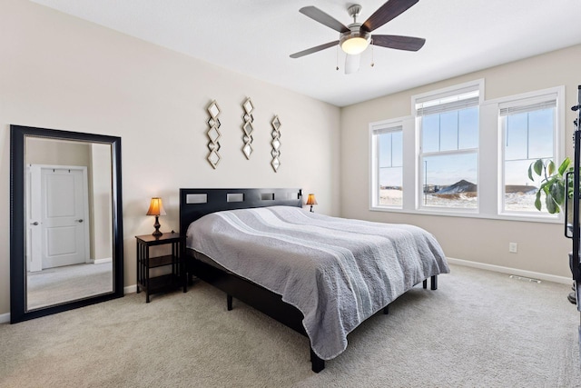 bedroom with light carpet, ceiling fan, visible vents, and baseboards