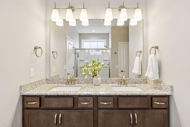 bathroom with a sink, a shower stall, and double vanity