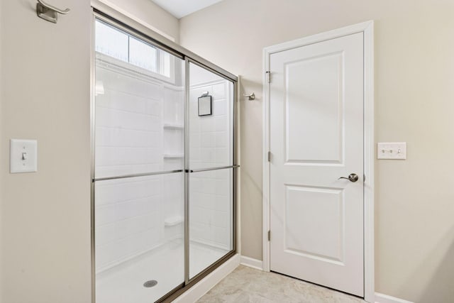 bathroom featuring a shower stall and baseboards