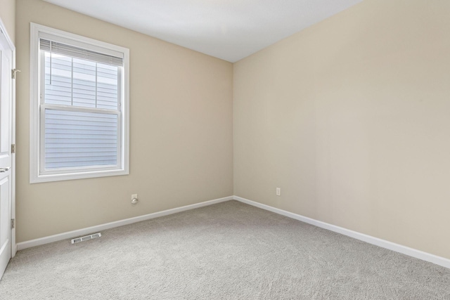 carpeted spare room with visible vents and baseboards