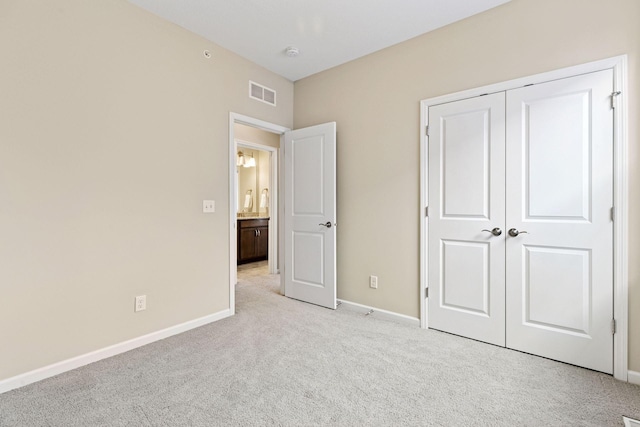 unfurnished bedroom featuring light colored carpet, a closet, visible vents, and baseboards