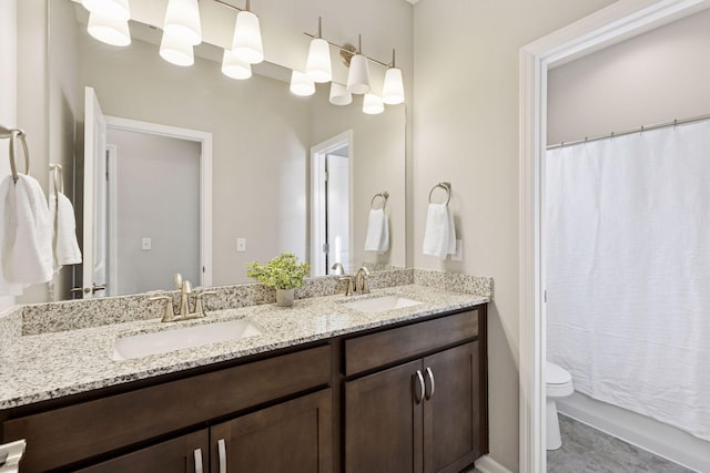 full bathroom featuring double vanity, a sink, and toilet