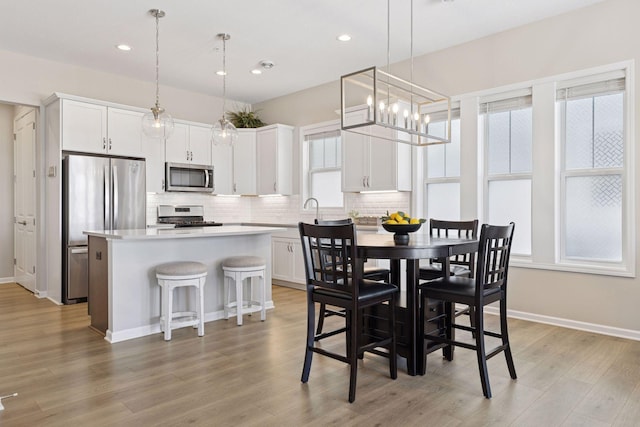 dining area with a chandelier, recessed lighting, light wood-type flooring, and baseboards