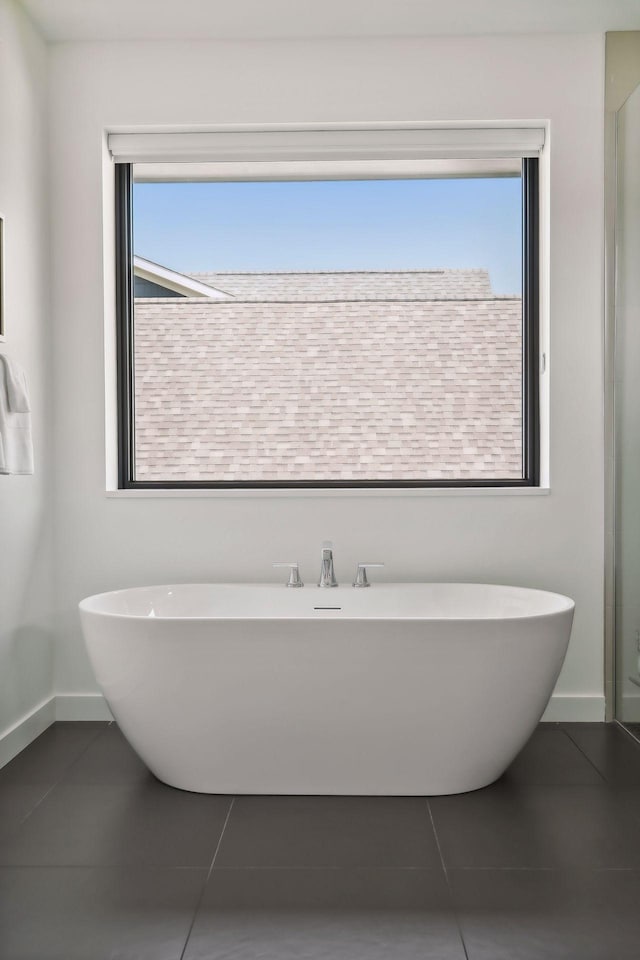 full bathroom with tile patterned flooring, a soaking tub, and a healthy amount of sunlight