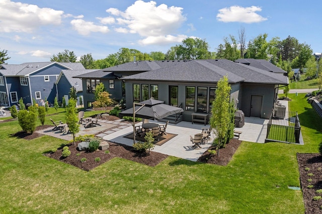 rear view of property featuring a yard, roof with shingles, a patio, and fence