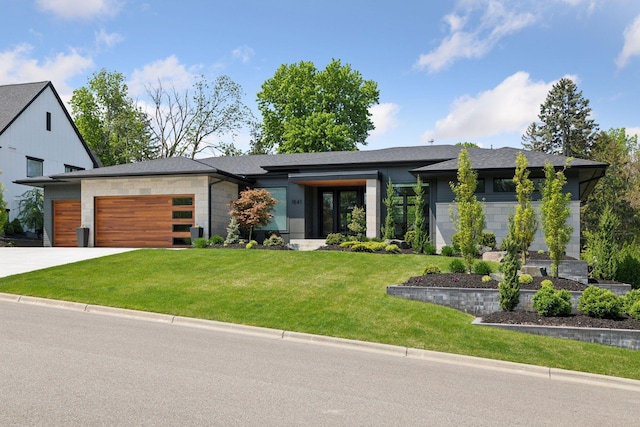 view of front facade featuring concrete driveway, stone siding, roof with shingles, an attached garage, and a front yard