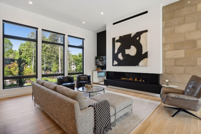 living area with a glass covered fireplace, plenty of natural light, light wood finished floors, and recessed lighting