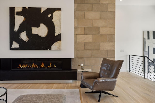 sitting room featuring a lit fireplace and wood finished floors